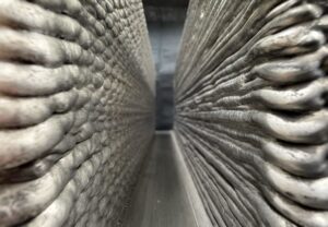 Close-up of metal additive manufacturing deposit showing layered bead texture and build direction