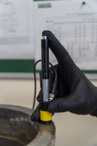 Close-up of an Equotip Leeb hardness tester probe positioned on a steel component prior to portable hardness testing.
